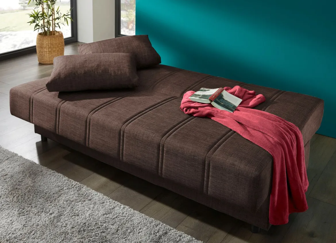 Frei im Raum aufstellbares Schlafsofa mit Dekokissen und Bettkasten
